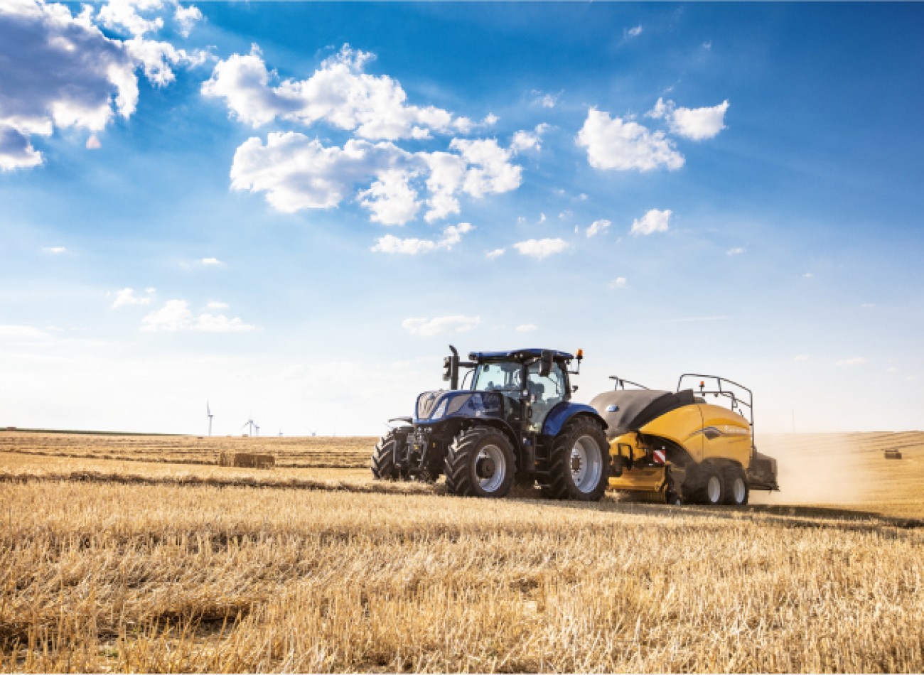 Presse à balles rondes attachée à un tracteur New Holland du Groupe Huot Agriculture